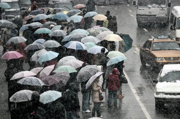 Passengers wait for a bus during heavy snow