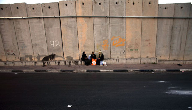A-Ram, West Bank: Palestinian women are wait for local transport by the separation wall