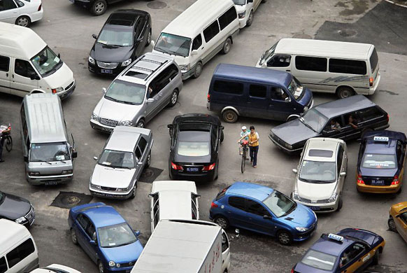 Beijing, China: A woman with a child on her bicycle navigates through snarled traffic in the central business district