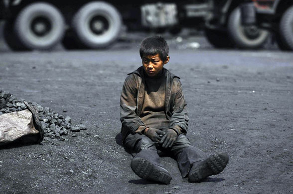 Changzhi, China: A child rests after searching for usable coal at a cinder dump site