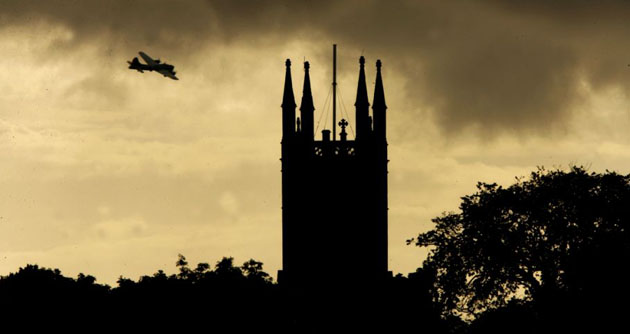 Prestwick, UK: Liberty Belle, a  B17 'Flying Fortress' airplane flies past a church building