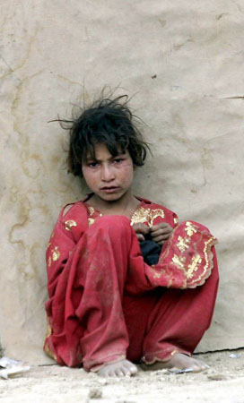 kabul, Afghanistan: A refugee girl sits outside her temporary shelter at a refugee camp