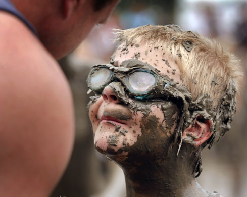 Michigan, US: Danny Sullivan, eight, with his father at the annual Mud Day celebration in Westland. The event consists of 200 tons of topsoil mixed with 20,000 gallons of water and about 1,000 children. Photograph: Bill Pugliano/Getty Images