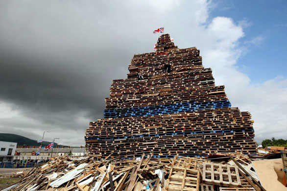 Belfast, Northern Ireland: A youth prepares to add the finishing touch to a massive bonfire in the Donegall Road area