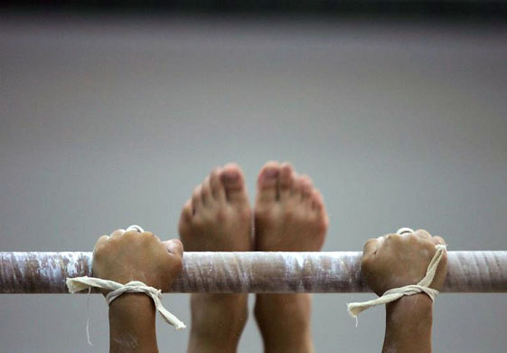 Beijing, China: A young girl practices on a bar during gymnastics training