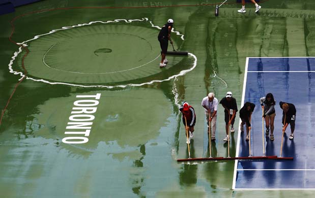 Workers wipe the court during a rain delay