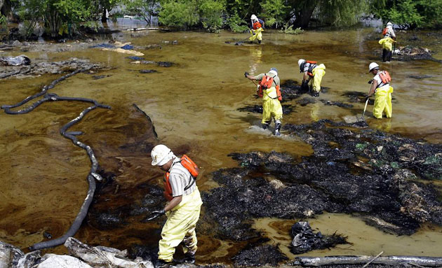 Jesuit Bend, US: Workers use absorbent mops to soak up fuel oil on a bank of the Mississippi river
