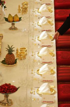 London, UK: A member of staff lays the State Banquet table in the ballroom at Buckingham Palace