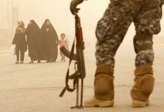 Baghdad, Iraq: A policeman stands guard as Shi'ite pilgrims march towards Imam Moussa al-Kadhim shrine