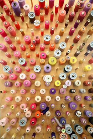 London, UK: Reels of coloured threads line the wall in the alterations department at Angels The Costumiers