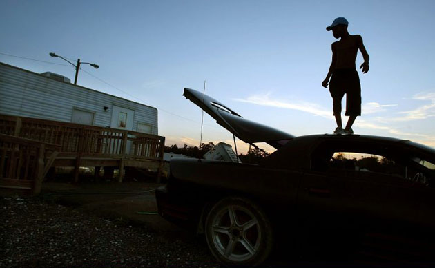 Adrian Cross, 10, stands on top of his parent's packed car as they prepare to move out of their trailer in FEMA Diamond trailer park