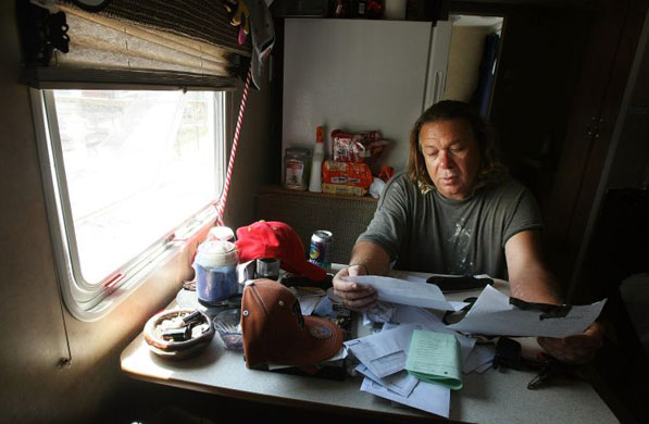 Michael St. Ann reads FEMA notices posted on his trailer door in the FEMA Diamond trailer park, Louisiana