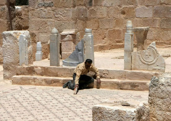 worker cleans the mosaic of the oldest church in the world, in the town of Rehab