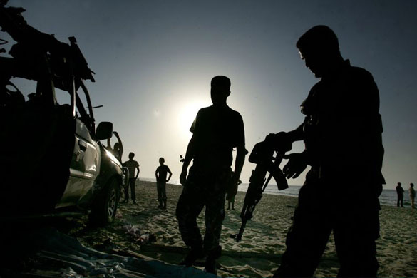 Hamas security officers inspect a destroyed 4x4 after it was targeted by an Israeli air strike