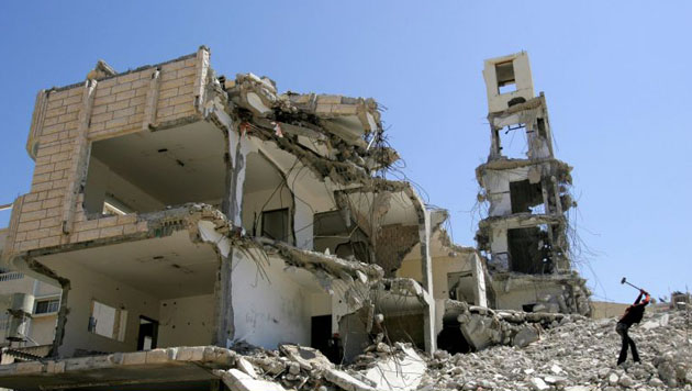 A Palestinian boy hammers concrete in the rubble of the Interior Ministry building to extract iron and floor tiles to sell on