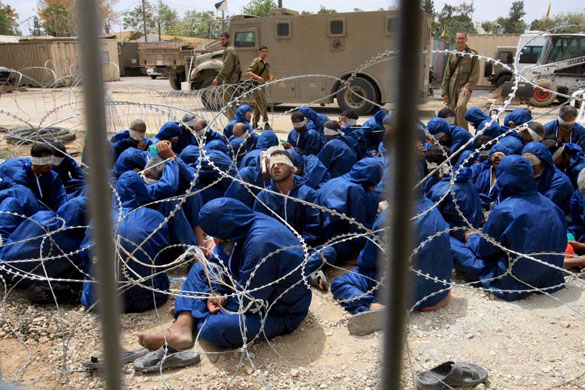 Blindfolded arrested Palestinians wait at an Israeli army base at the southern Gaza Strip border with Israel