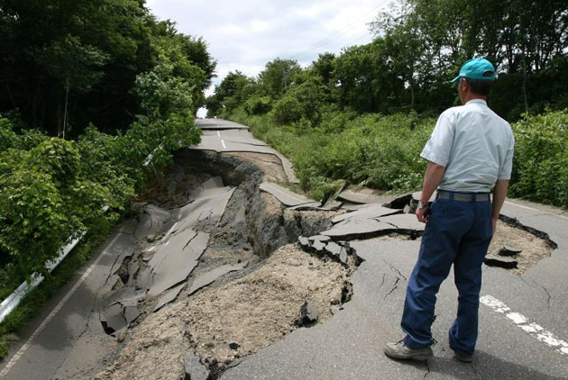 A local resident examines damaged road in Oshu