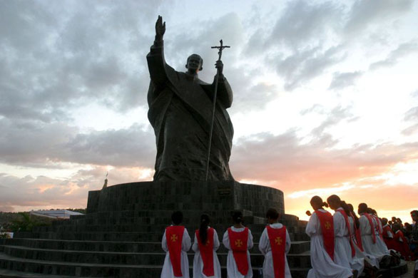 Tasitolu, East Timor: Children pray during a ceremony at the statue of the late Pope John Paul II