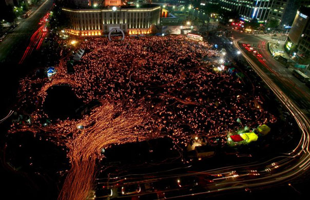 Protesters hold candles as they march on the main street during a protest rally in Seoul against beef imports