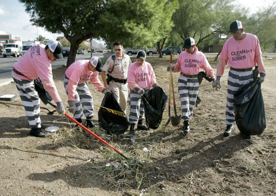 Arizona, US: Members of the Maricopa County chain gang clean a trench in Phoenix. Men convicted of drunken driving clean busy streets in full view of commuters and perform burials in indigent cemetaries.
