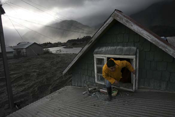  A man leaves via a window of his flooded house in a deserted town in southern Chile