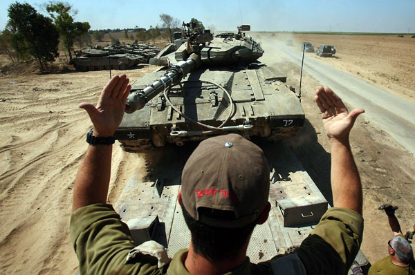 Kibbutz Ein Hashlosh, Israel: An Israeli soldier directs a Merkava tank onto a flatbed truck in an army camp along the border with Gaza Strip