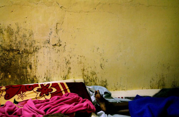 Cape Town, South Africa: A sick Somalian refugee lies in a makeshift bed inside a toilet at Soetwater refugee camp