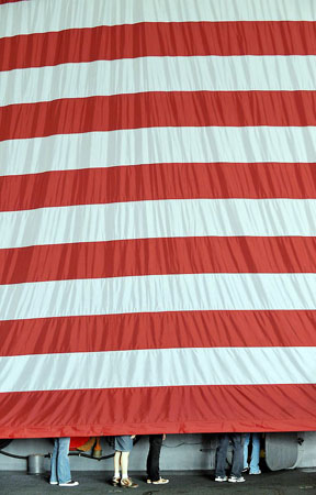 Hong Kong: Navy personnel walk behind a US flag in the hangar of the USS Ronald Reagan which is berthed at the mouth of Victoria Harbour