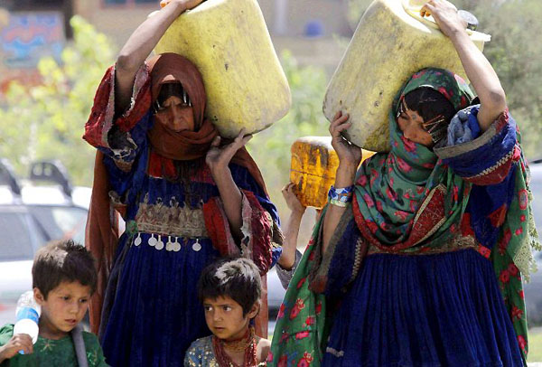 Kabul, Afghanistan: Women carry drinking water to a refugee camp
