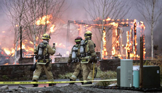 Woodinville, US: Firefighters walk past the remains of a house still in flames