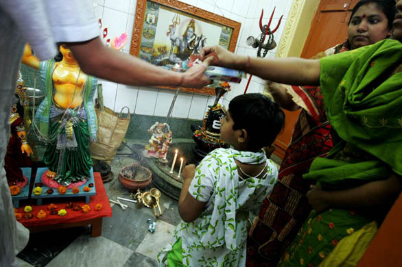 Dhaka, Bangladesh: A woman buys incense sticks and candles before offering prayers at the alter of Lord Shiva