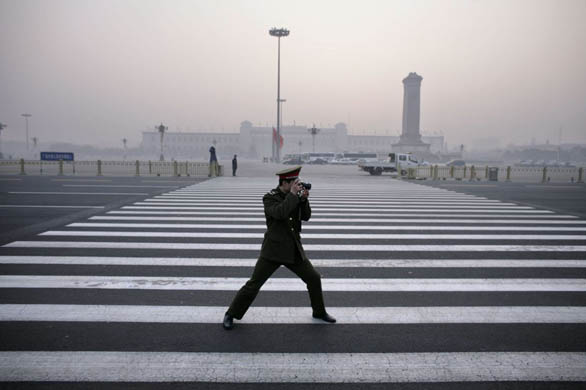 A paramilitary police officer takes a picture of his friend outside the Great Hall of the People