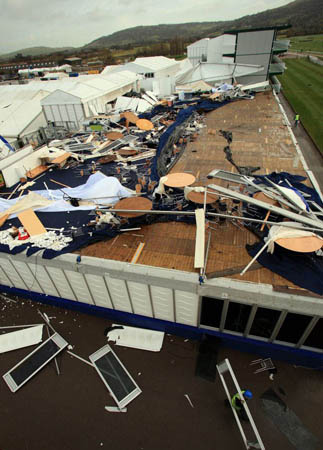 Workers begin to tidy up a damaged area of Cheltenham Racecourse