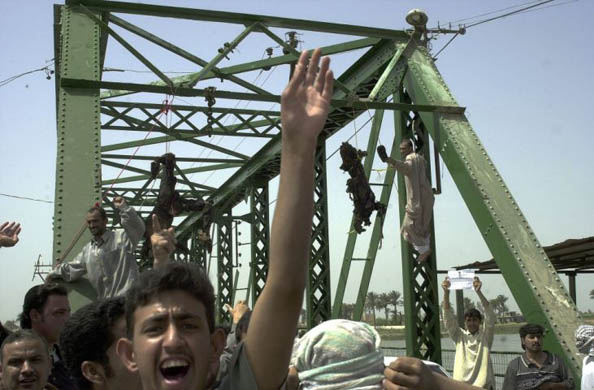 Iraqis chant anti-American slogans as charred bodies hang from a bridge over the Euphrates river