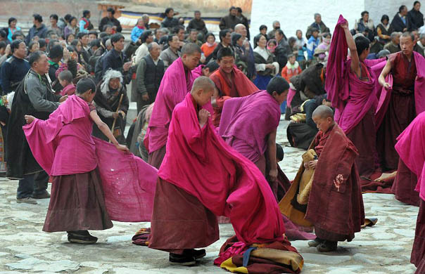 Tibetan Buddhist monks leave a ceremony watched by Buddhist pilgrims at the historic Labrang monastery