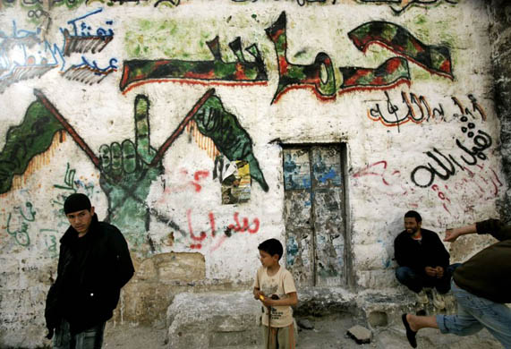 Palestinians gather by a house decorated with graffiti supporting the Islamic movement Hamas