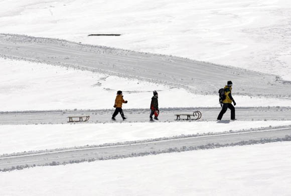 Altenberg, Germany: People walk with their sledges over snow covered meadows