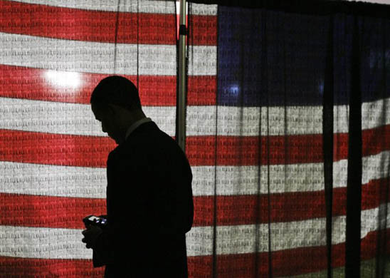 Barack Obama looks at his wireless device as he waits to speak at a town hall meeting