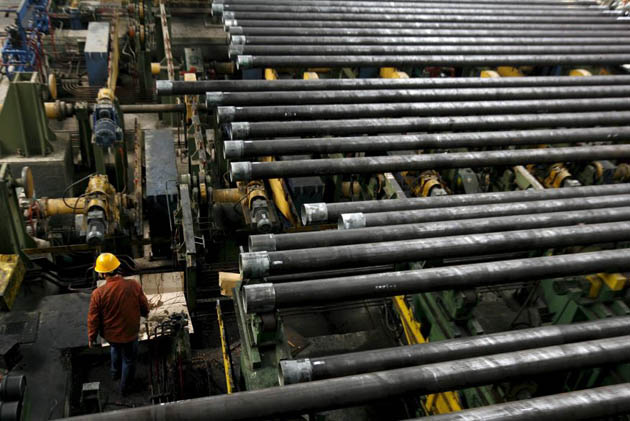 Chengdu, China: A worker walks through a seamless steel pipe factory