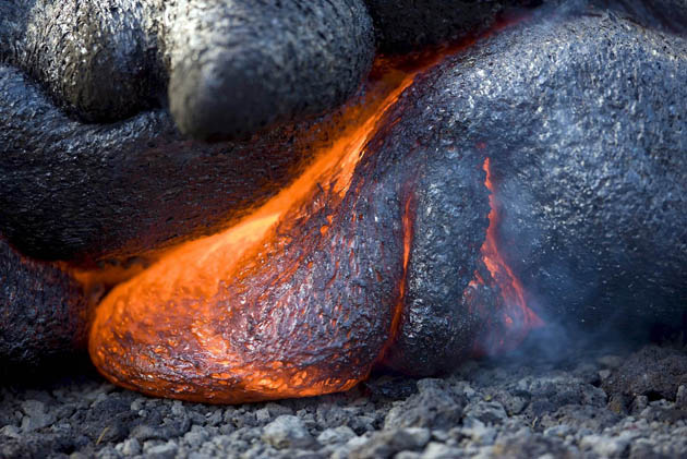 Molten lava oozes from beneath the hardened crust of the cooled edge of the flow through the Royal Gardens Subdivision