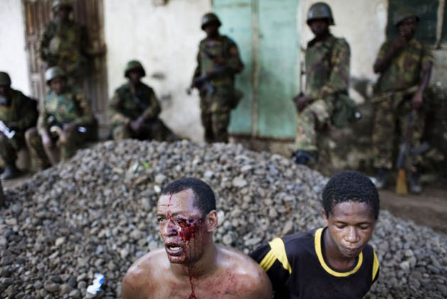 Two men sit on the ground after being arrested under suspicion of collaborating with renegade Anjouan leader Mohamed Bacar