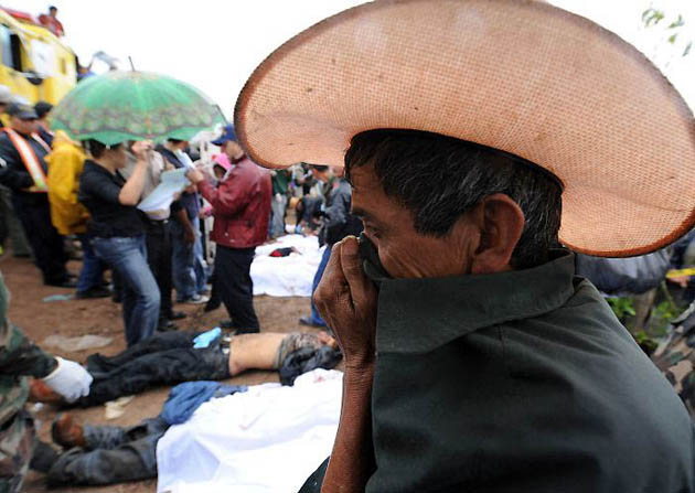 A man covers his face to mask the the smell from the bodies of victims of an accident involving a bus on the route linking San Isidro with Jesus de Oterowhich