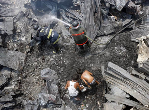 Manila, Philippines: Fire victims collect belongings at a shanty town