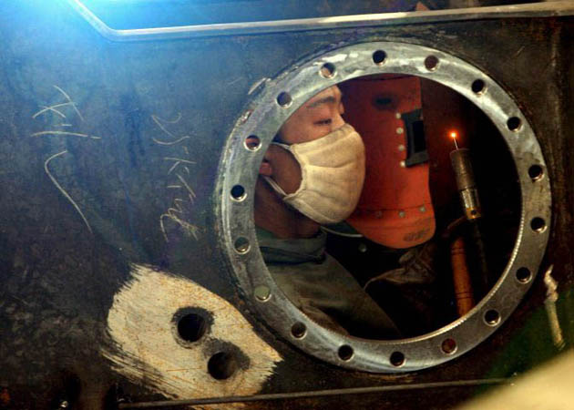 Xuzhou, China: A man works in the production line at the Xuzhou Construction Machinery Group