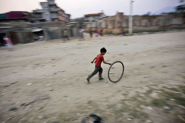 A Nepalese boy runs as he plays with a wheel