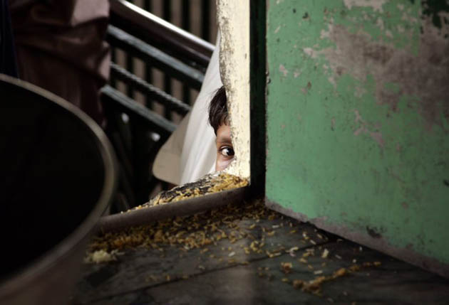 A young boy waits for free rice provided at the Bari Imam Shrine 