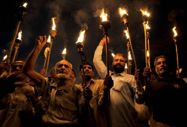 Activists from Pakistani labour Unions hold lighted torches during a march