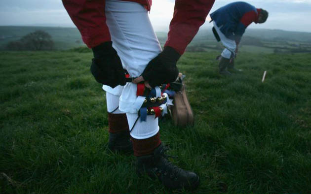 A Priston Jubilee Morris Man adjusts his bells as he prepares to dance at dawn at the locally known One Tree Hill