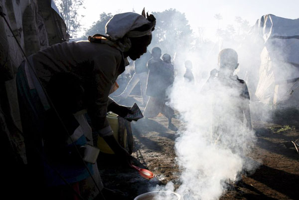 Nakuru, Kenya: A mother prepares a cup of tea over an open fire at an internally displaced person's (IDP) camp