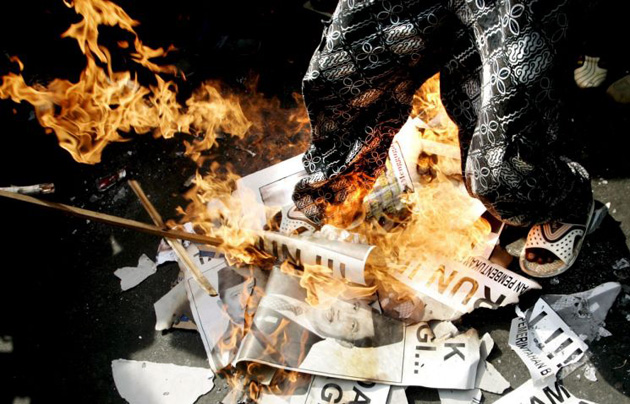 An Indonesian student steps on  burning posters